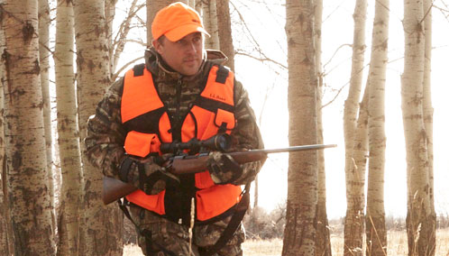 A hunter wearing L.L.Bean’s BOA Technical Big-Game Vest and carrying a rifle.